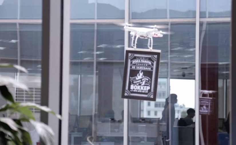 Drone carrying an advertising banner during a delivery-style brand stunt above a city.