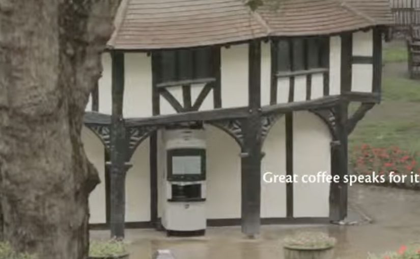 A talking coffee vending machine draws a small crowd as it chats with passers-by in a public square.