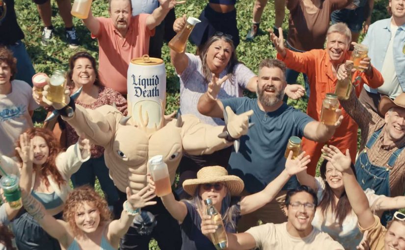 Jason Kelce, the Liquid Death mascot and a crowd hold jars during the Garage Beer and Liquid Death “We Want Your Pee” campaign.